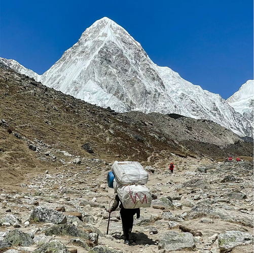 A man carrying a heavy bag goes to a supply station on the mountain to replenish goods